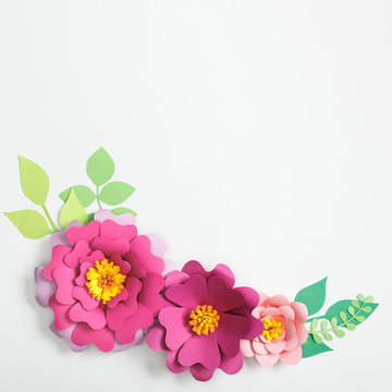 top view of multicolored paper flowers and leaves on grey background