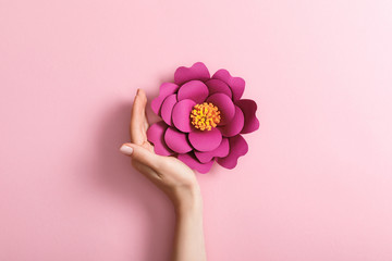 cropped view of female hand near paper flower on pink background