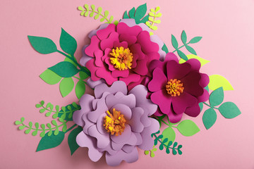top view of paper colorful flowers and green leaves on pink background