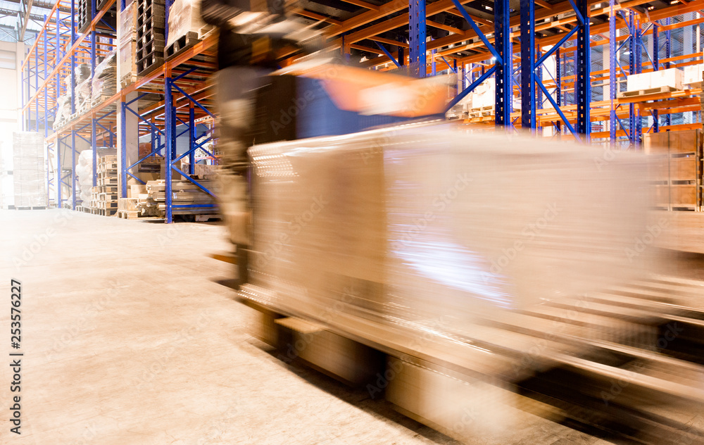 Wall mural Blur Motion of Workers Driving Forklift Unloading Cargo Pallets in The Warehouse. Shipping Warehouse. Delivery Service Shipment Boxes. Supply Chain Goods. Warehouse Cargo Logistics Transport.	