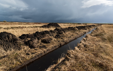 Cultivated peat bog bricks stacked for drying in rural Irish landscape