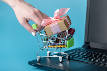 Daily purchases in the shopping cart on the laptop keyboard on a blue background. Online shopping