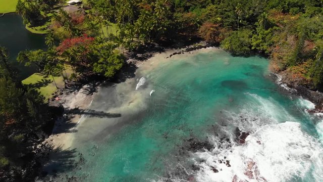Aerial of shipman beach puna hawaii black sand white sand mixed.  Electric blue water waves breaking