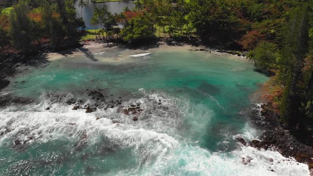 Aerial of shipman beach, a beautiful hidden cove on the island of Hawaii. Perfect ultra blue water with surrounding black and white sand mix beach :)
