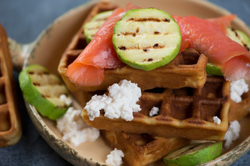 Breakfast with belgian waffles, red fish fillet, ricotta cheese and fried zucchini slices, closeup, selective focus