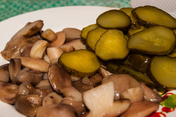 Marinated boletus mushrooms and cucumbers gherkins close-up