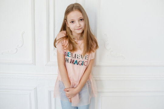 Cute pre-teen girl wearing fashion clothes posing in white interior