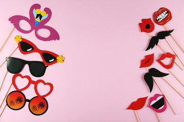 Different photo booth props on bright pink background. Paper moustache, lips and glasses on stick....