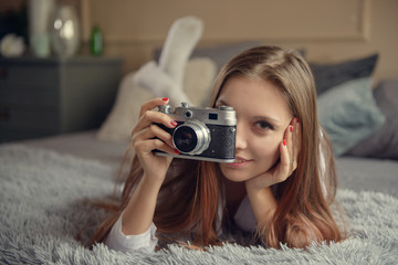 Girl with a camera is lying on the bed