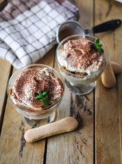 Classic tiramisu cake in a glass with fresh mint, on wooden background
