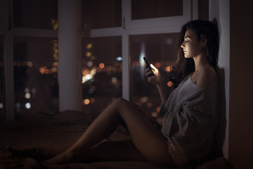 Woman use of mobile phone indoors at night - Powered by Adobe