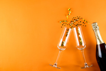 Bottle of champagne, flute glasses with confetti, streamers and other party attributes in flat lay...