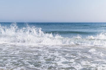 Fototapeta premium Sea surf with white foam and spraying water drops in the air. Seascape of Black Sea in February on a sunny day.