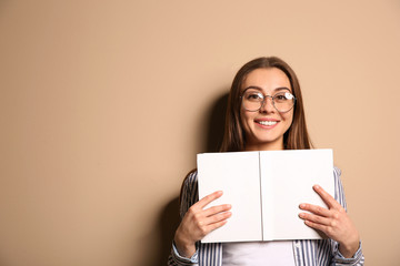 Young woman with book on color background, space for text