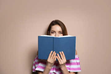 Fototapeta premium Young woman with book on color background