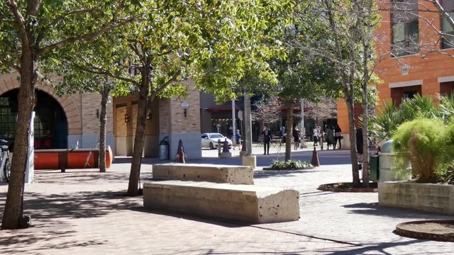 A man jogging through a small town square meeting place with trees and buildings