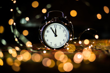 Obraz na płótnie Canvas alarm clock on the eve of the holiday shrouded in garland