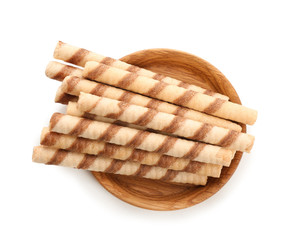 Plate with tasty wafer roll sticks on white background, top view. Crispy food