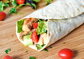 Delicious fresh chicken wrap, closeup shot. Tasty tortilla with salad and turkey meat,healthy eating scene. 