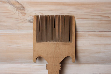 Comb from wood for flax and hemp on the background of the wall type bleached oak