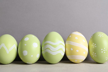Painted Easter eggs on table against color background, space for text