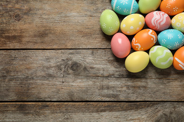 Fototapeta na wymiar Many colorful painted Easter eggs on wooden background, top view. Space for text