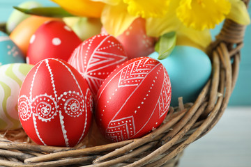 Painted Easter eggs in wicker basket, closeup