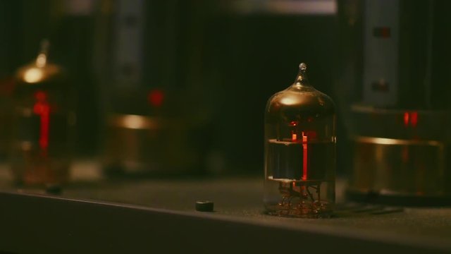 Pan right and focus pull along glowing valves on music amplifier