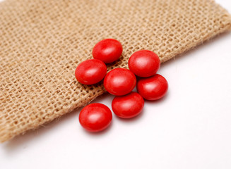 multivitamin red dragees on a jute bag background