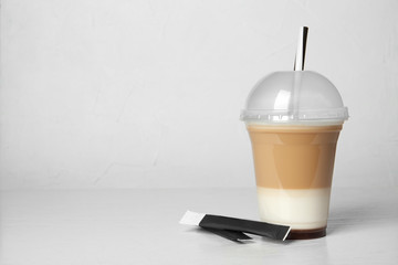 Plastic cup of tasty caramel macchiato on table, space for text