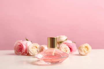 Bottle of perfume with beautiful roses on table
