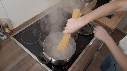 Young woman cooks spaghetti in the kitchen