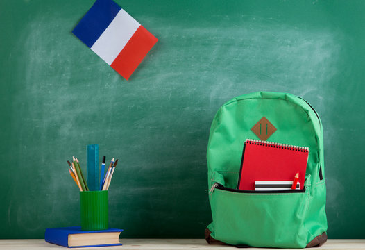 backpack, flag of the France, book and school supplies on the background of the blackboard