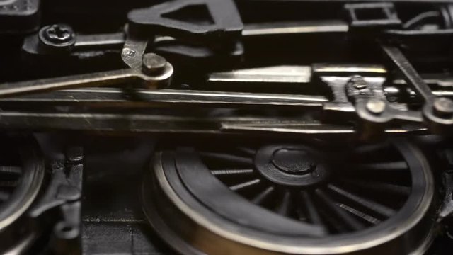 Minature electric powered model steam locomotive driving wheels and connecting rods start turning then accelerate before coming to a stop.