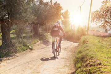 Biker person on a bicycle practicing sports in the nature against a sun flare. Lifestyle and active concept with empty copy space for Editor's text.