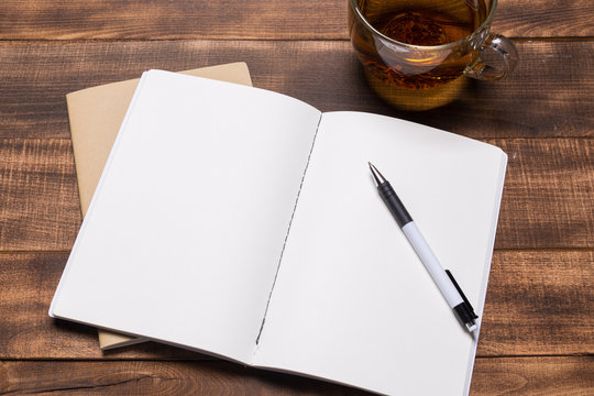 top view image of open notebook with blank pages next to cup of coffee on wooden table. ready for adding text or mockup.