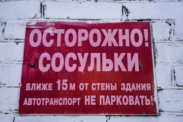 Red warning sign. The inscription on it reads: Beware the icicles! No parking space nearer 15 m from the building's wall!