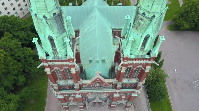 Aerial, tilt up, drone shot of St Johns Church, revealing the Helsinki cityscape, on a cloudy, summer day, in Ullanlinna, Helsinki, Finland