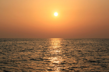 Beautiful sunrise cloudscape over sea background. Sun rays beaming through picturesque clouds