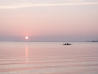Fototapeta premium Rowboat and sunset on the sea