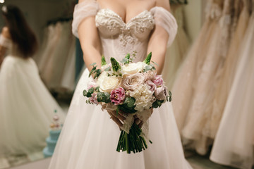 Bouquet holding by Bride she wear white wedding dress at wedding shop