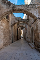 Fototapeta na wymiar Street and alley with a arches view of colorful houses in the old town. A region of Apulia. Monopoli, Puglia, Italy 