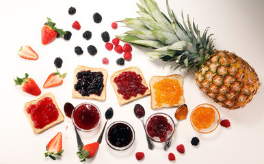 assortment of jams, seasonal berries, plums, mint and fruits in glass jar