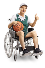 Fototapeta premium Disabled elderly man in a wheelchair holding a basketball and showing thumbs up