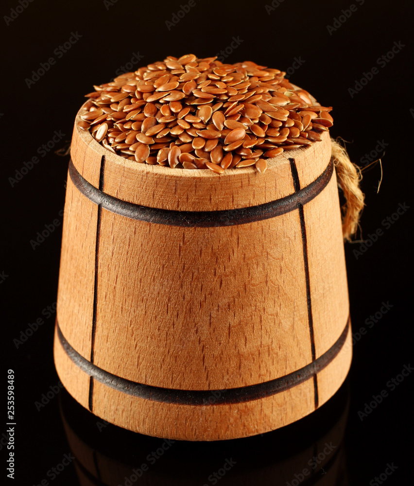 Sticker Seeds of flax in a barrel on a black background