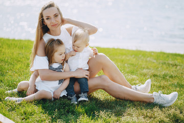 Fototapeta premium a beautiful young long-haired mom in the park with her beautiful little son and charming daughter