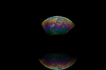 Reflection of a bubble in rainbow colors on a black background.