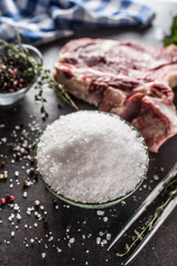 Sea salt in bowl with raw beef meat pepper and herbs