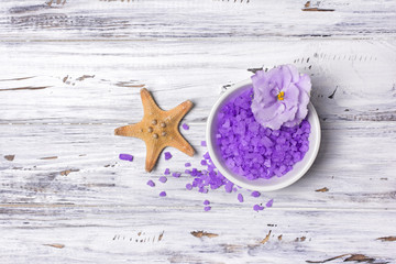 Flavored purple sea salt crystals with violet flower and starfish on white