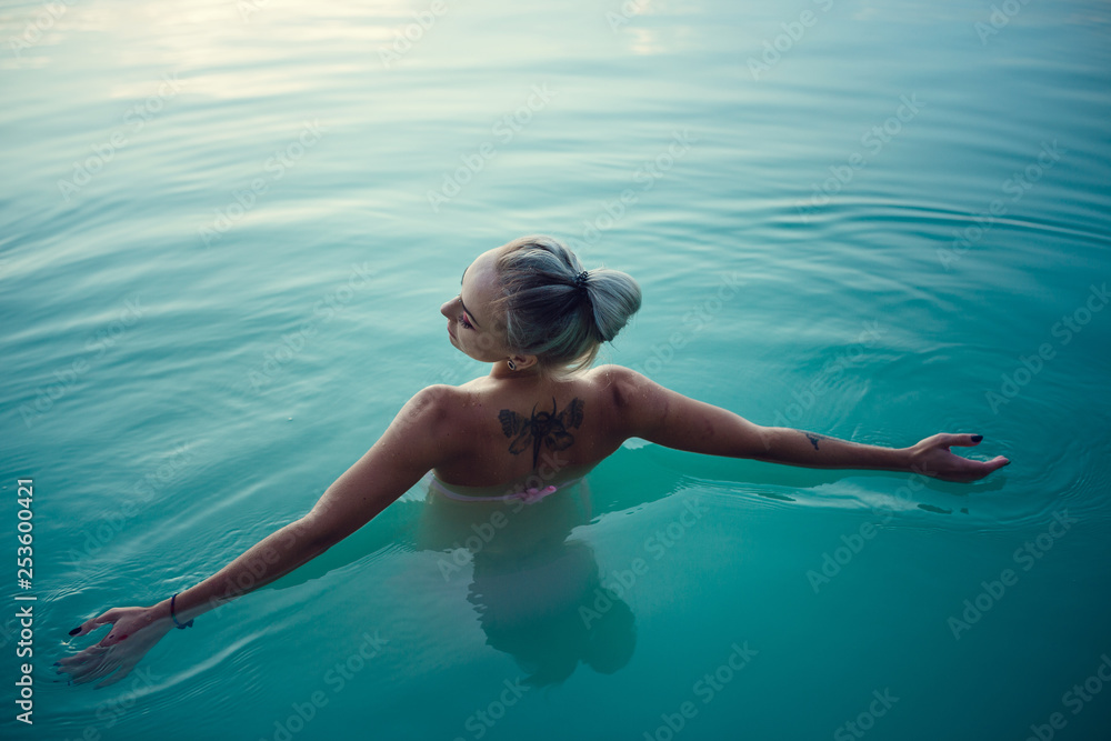 Wall mural beautiful and young woman at sunset in the lake